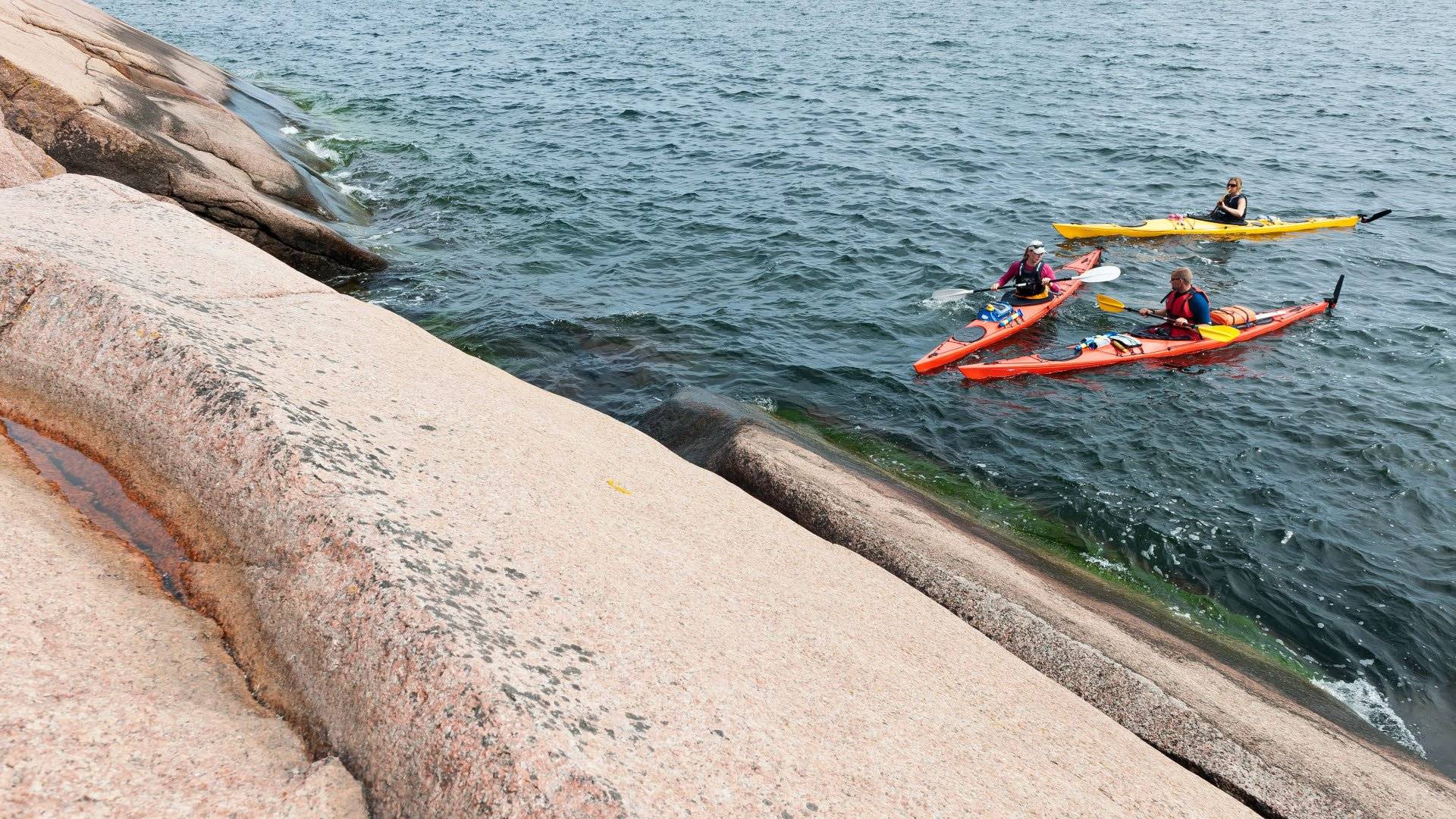 Paddlare på havet vid en klipphäll, Blå Jungfruns nationalpark, Kalmarsund. 